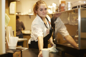 smiling kitchen worker reaching for a coffee cup